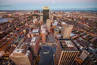 A photograph of an aerial view of Boston, with the John Hancock tower in the foreground.