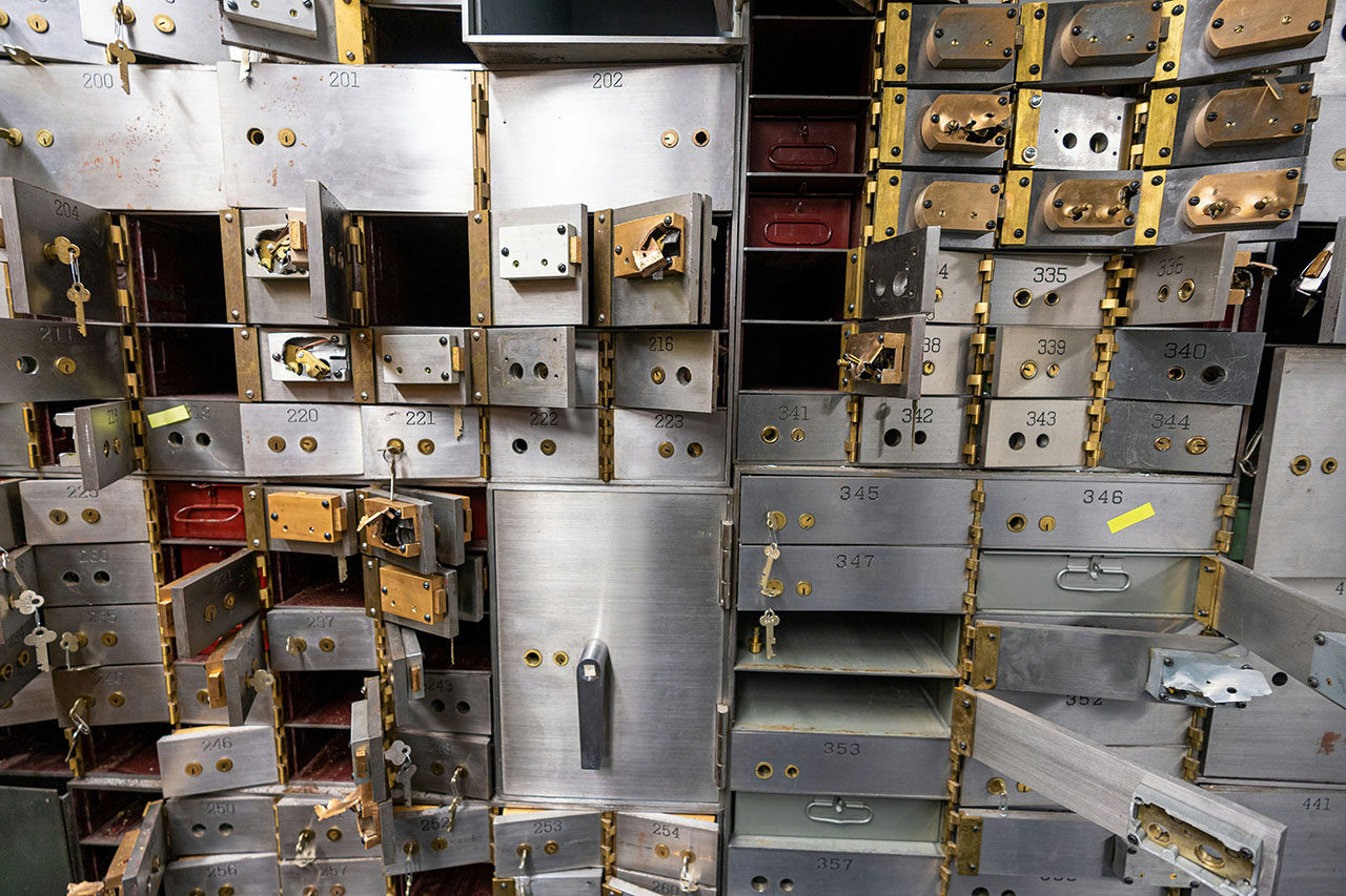 A photo of a wall of safe deposit boxes, most of which are open and empty. 