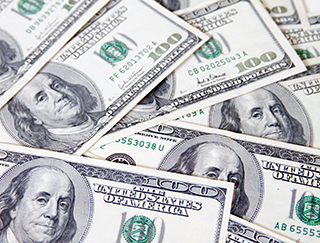 Close-up of a pile of one-hundred dollar bills that are spread out on a surface.