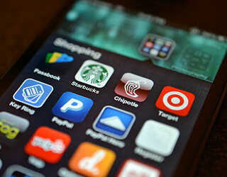 A close-up of the screen of a smartphone that has many colorful shopping apps open.