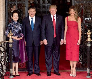 Two smiling, suit-wearing gentlemen are flanked by two elegantly-dressed attractive women.