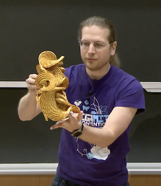 Prof. Demaine holds up a swirling origami figure.