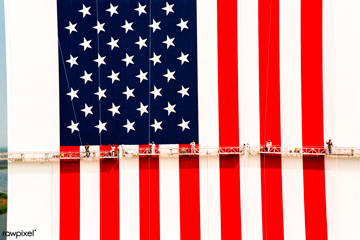 workers with painting rollers and brushes, suspended on platforms to repaint a giant national flag of USA on a building