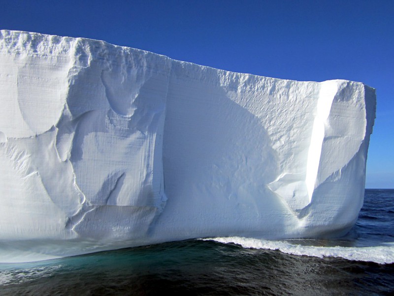 an iceberg floating in the ocean under a sunny sky