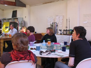 students sitting around tables, paying attention to a lecturer (not pictured)